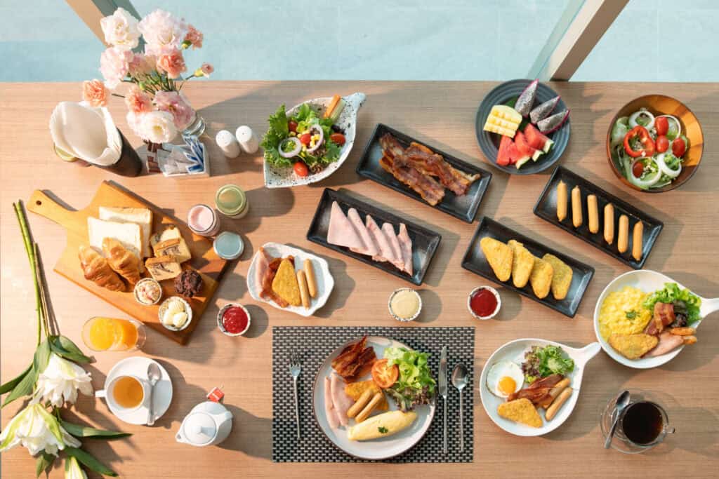 Lavish breakfast spread at Aviyana Hua Hin Hotel featuring fresh fruits, salads, bread, eggs, bacon, and beverages, highlighting a luxurious hotel dining experience in Hua Hin.